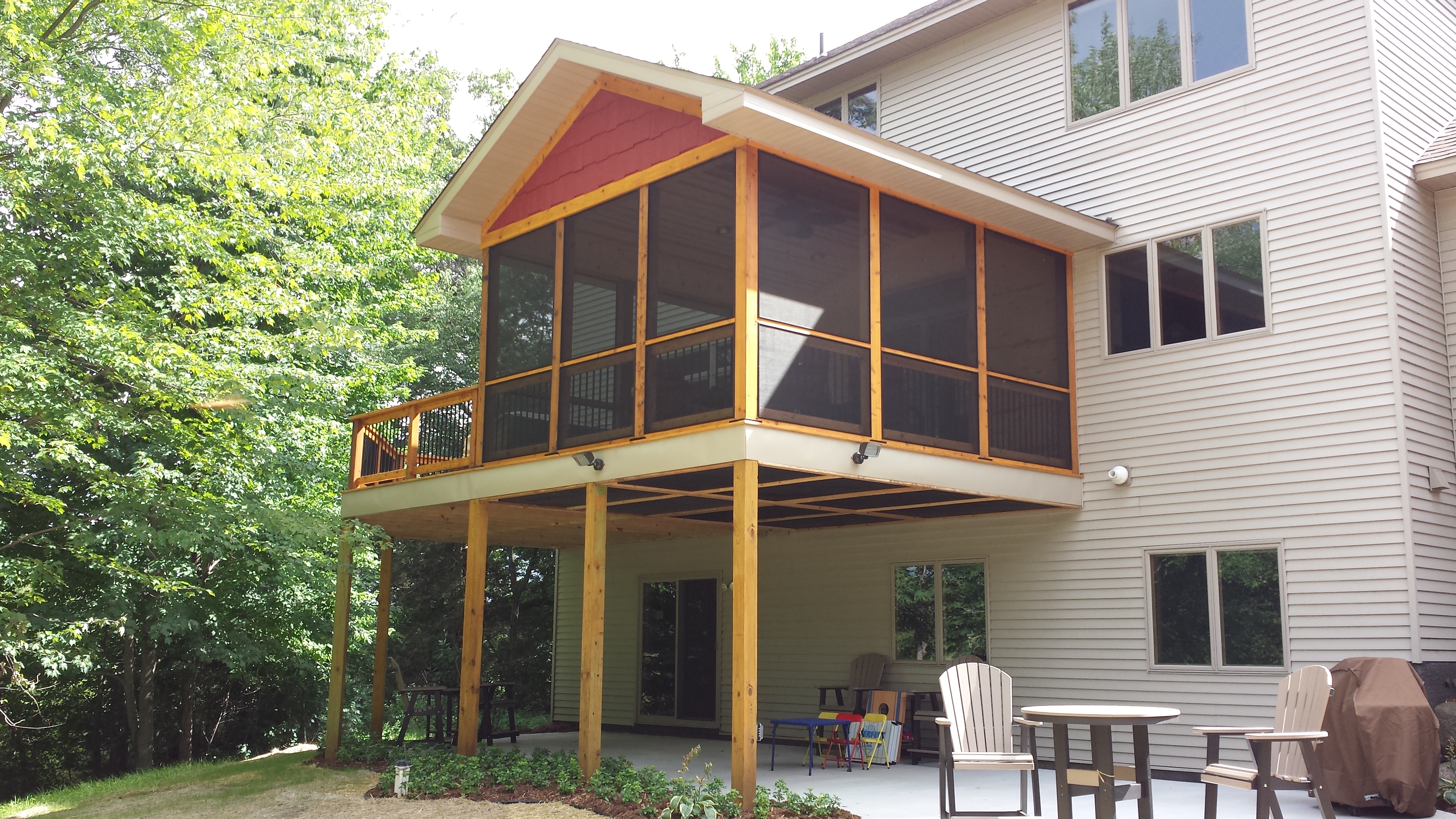 Screened upper porch with covered patio below on a two-story home